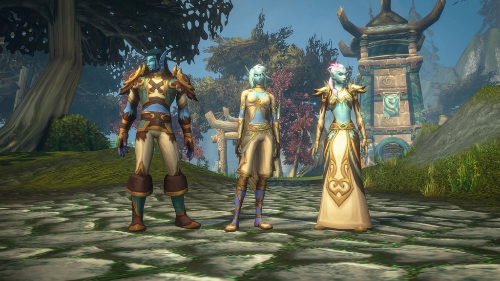 Trzy postacie rasy Skyborne w World of Warcraft: Forever stoją na kamiennej ścieżce, prezentując różne fryzury, odcienie skóry i stroje w kolorach złota, kremu i turkusu. W tle widać drzewa oraz kamienne wieże z zakrzywionymi dachami. Źródło: Blizzard Press Center.