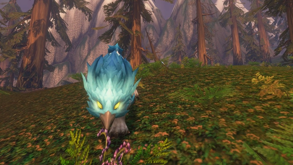 Niebieski prideclaw o jaskrawożółtych oczach i zakrzywionym dziobie zajmuje pierwszy plan leśnego kadru. Źródło: World of Warcraft: Forever, zrzut ekranu gracza.