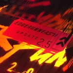 Grafika promocyjna aktualizacji 2.5 do Cyberpunka 2077. Czerwona tabliczka z napisami „Edgerunners” i „Update 2.5” na abstrakcyjnym tle w odcieniach czerni, czerwieni, pomarańczu i żółci, z efektem cyfrowych zakłóceń. Źródło: CD PROJEKT RED / Cyberpunk.net.